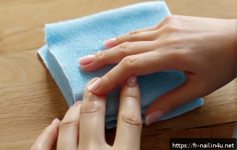 젤 네일 리무버 패드 사용 방법 - A close-up scene of a French woman gently removing gel nail polish at home using acetone-soaked remo...